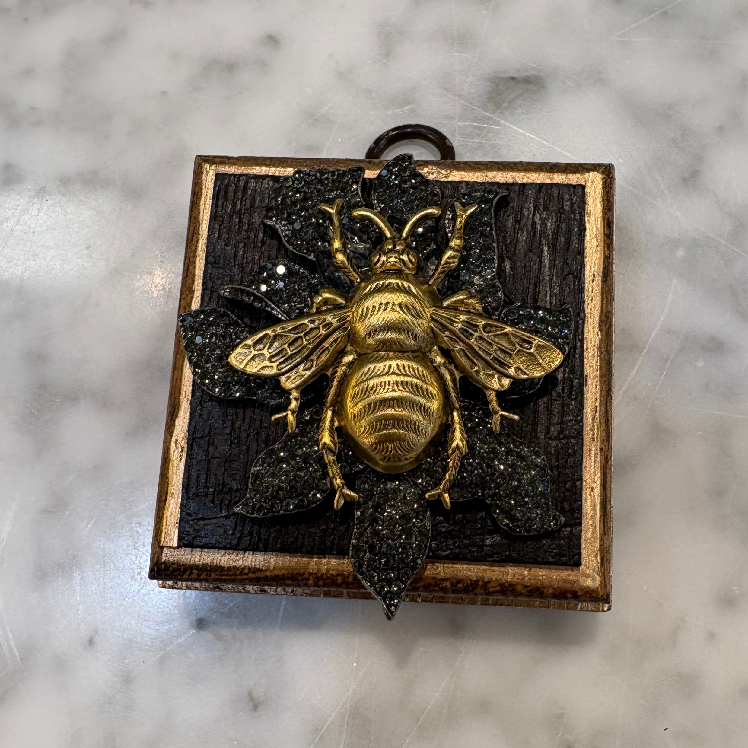 Museum Bees - Gold bee on top of black stones