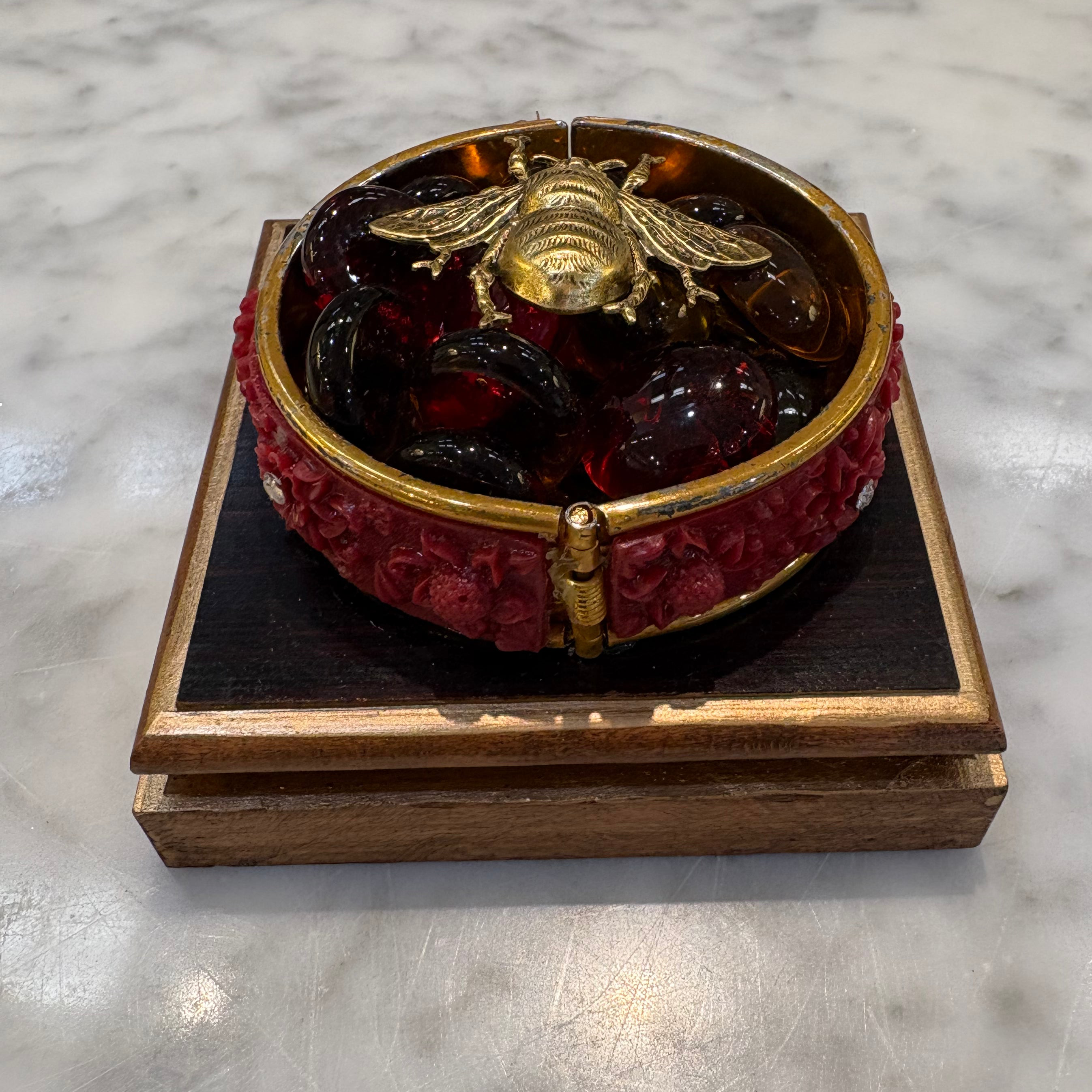Museum Bees - Gold Bee on top of red stones in a red bracelet